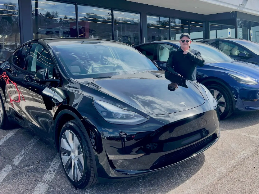 Mark April, owner and operator of Niwot Executive Transport, standing with his black Tesla Model Y